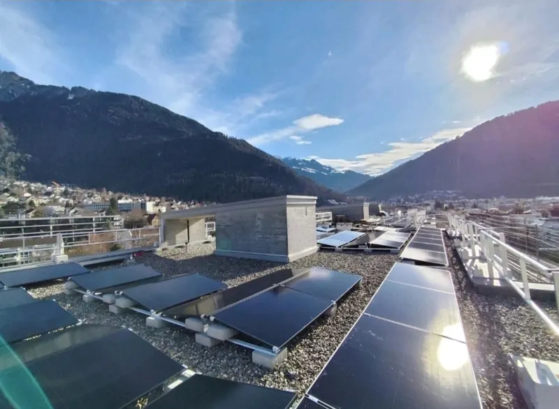 Aufdach-Solaranlage auf einem Flachdach, im Hintergrund die Alpen